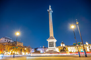 Nelson's Column stands tall in Trafalgar Square at night, illuminated by street lights. The monument commemorates Vice-Admiral Horatio Nelson's victory at the Battle of Trafalgar.