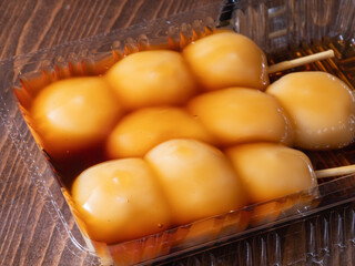 プラスチック容器に入っている和菓子。甘い醤油タレの"みたらし団子"のクローズアップ。