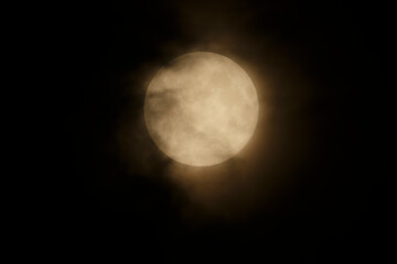 Majestic full moon illuminated by clouds on a clear night sky over an urban landscape