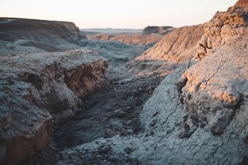 Arid landscape at sunset, showcasing textured clay formations and a rugged, desolate beauty.