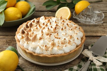 Delicious meringue pie, lemons and cake server on wooden table, closeup