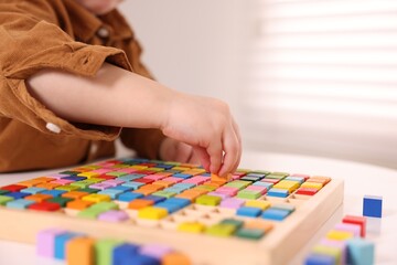 Fototapeta premium Motor skills development. Little boy playing with Times table tray indoors, closeup
