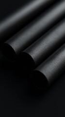 Fototapeta premium Three black tubes on a dark background.