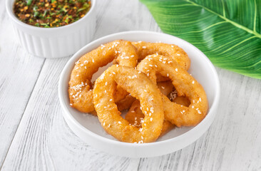 Crispy battered calamari rings with sesame seeds and spicy Asian dipping sauce