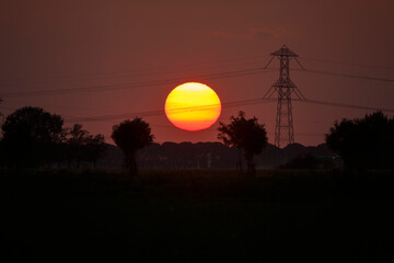 Vibrant sunset over a peaceful landscape with power lines silhouetted against the sky