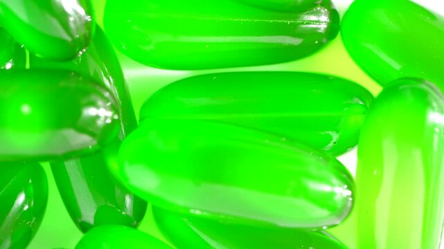 Vitamin e capsules kept on rotating disk. Close up of green vitamin e capsules on white surface.