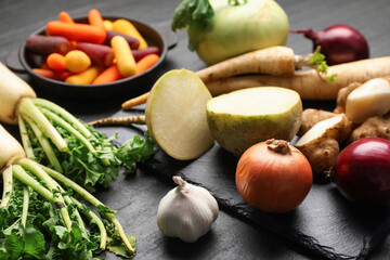 Different raw root vegetables on black table, closeup