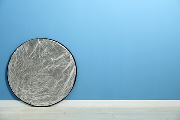 One light reflector near blue wall indoors, space for text. Photo studio equipment
