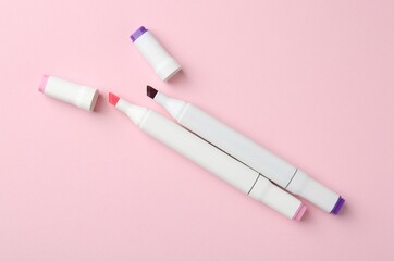 Colorful double sided markers on pink background, flat lay