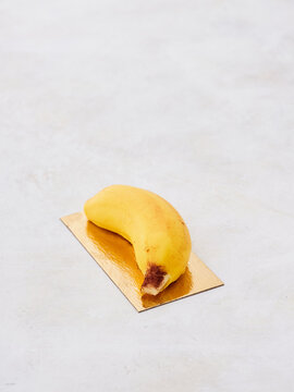 A striking yellow banana вуыыуке rests on a golden sheet, blending simplicity and elegance. The smooth surface beneath highlights the fruit's vivid color, creating a contemporary focal point