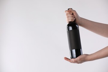 Woman with bottle of wine on white background, closeup. Space for text