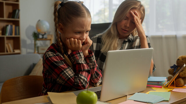 Stressed upset Caucasian mother woman female mom parent headache girl schoolgirl learner studying online laptop at home little pupil child e-learning difficulty daughter kid educational problem family