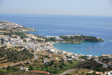 Panoramic view of Agia Pelagia in Crete, Greece from above with the blue sea and the clear blue sky in the background - Holiday homes, villas and hotels with swimming pools amidst beautiful vegetation
