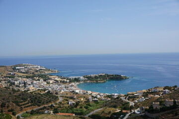 Fototapeta premium Panoramic view of Agia Pelagia in Crete, Greece from above with the blue sea and the clear blue sky in the background - Holiday homes, villas and hotels with swimming pools amidst beautiful vegetation
