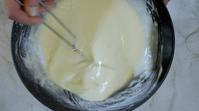 Food preparation. Top dow view, close-up of thin pancake, crepe batter preparation. Slow motion footage 100fps.