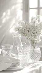 White flowers in a crystal vase, surrounded by elegant glassware on a sunlit table.