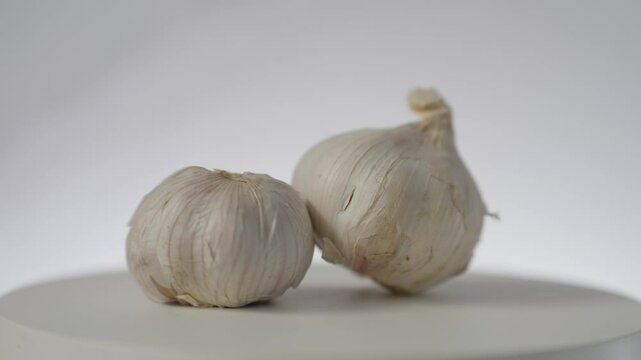 Fresh garlic cloves arranged neatly on a rotating tray, White garlic bulb composition