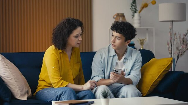Teen son helping his mother with a new phone app, fixing gadget issues together