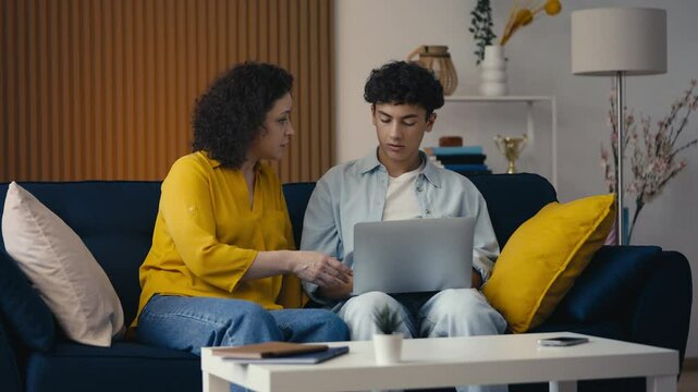 Mom and her teen son browsing internet on a laptop, choosing a university online