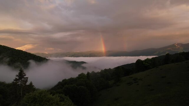 Low clouds and the rainbow at the sunrise in mountains dron landscape