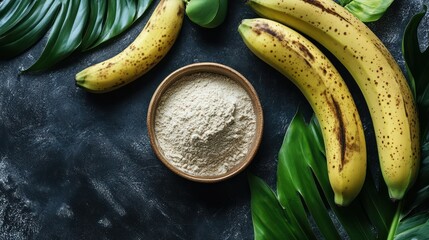 Banana powder in bowl with fresh bananas and tropical leaves