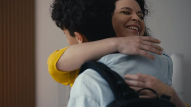 Excited mother hugging her teenage son, happy to see him home from college