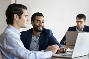 Two young colleagues collaborating, sharing ideas or reviewing new business platform on laptop, developing marketing strategy, working on joint online presentation met coworking office. Task execution