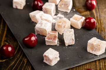 sweet Turkish delight slices with cherry slices on a black slate board