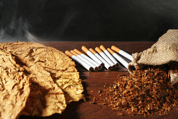 Tobacco, dried leaves and cigarettes on wooden table