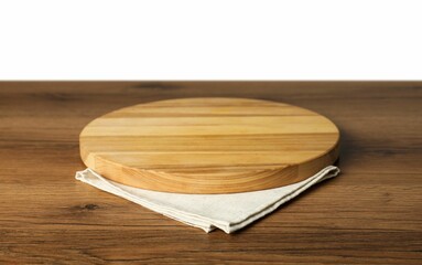 Light napkin and empty board on wooden table against white background