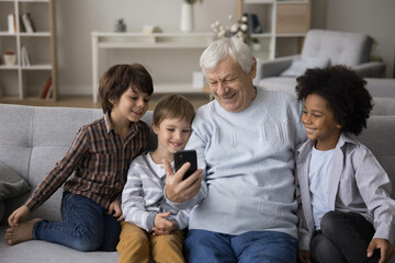 Modern tech and intergenerational family bonding. Loving elderly man grandparent gather three...