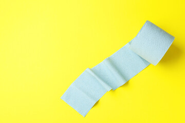 Light blue toilet paper roll on yellow background, top view. Space for text