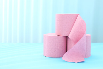 Pink toilet paper rolls on light blue background, space for text
