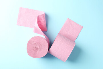 Pink toilet paper rolls on light blue background, top view