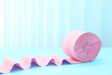 Pink toilet paper roll on light blue background. Space for text