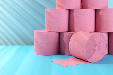 Pink toilet paper rolls on light blue background, closeup