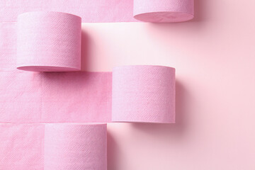 Color toilet paper rolls on light pink background, flat lay
