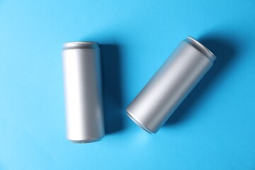 Two tin cans on light blue background, top view