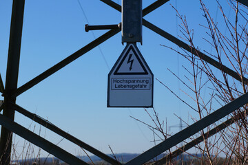 Warnschild an einem Strommast mit der Aufschrift Hochspannung Lebensgefahr