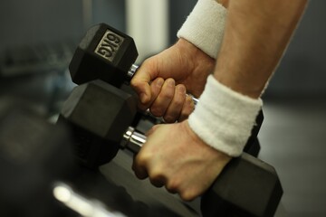 Athletic man training with dumbbells in gym, closeup