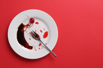Dirty plate and fork on red background, top view. Space for text