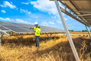 An engineer wearing safety gear inspects a large solar panel using a power drill under a vibrant...