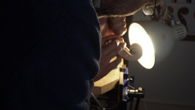 Luthier meticulously crafting a violin scroll in his workshop