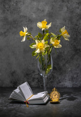 a bouquet of daffodils, a book and a clock on the table