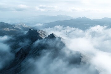 Obraz premium Mountains and wind turbines rise above a misty landscape in the clouds