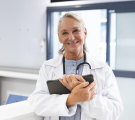 Smiling female doctor holding tablet in hospital, ready to assist patients