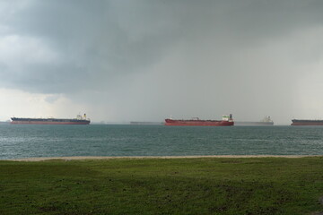Fototapeta premium A cargo ship navigates rough seas under a dark stormy sky. Waves crash against the vessel as strong winds and heavy clouds intensify the dramatic maritime scene. 