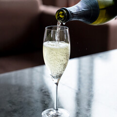 緑色のボトルからシャンパングラスにシャンパンを注ぐ瞬間 © n.s