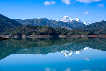 Beautiful landscape of lake and reflection of blue sky, clouds and mountains on surface of lake, Panoramic view of lake and snow-covered mountain and Forest trees calm in Jijel Algeria North African.