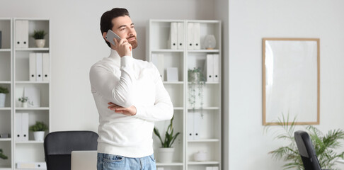 Thoughtful businessman talking by mobile phone in office